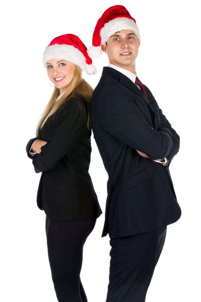 Young professional adults stand back to back wearing Santa hats