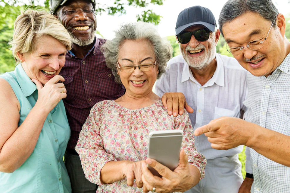 Diverse seniors having fun observing a cell phone